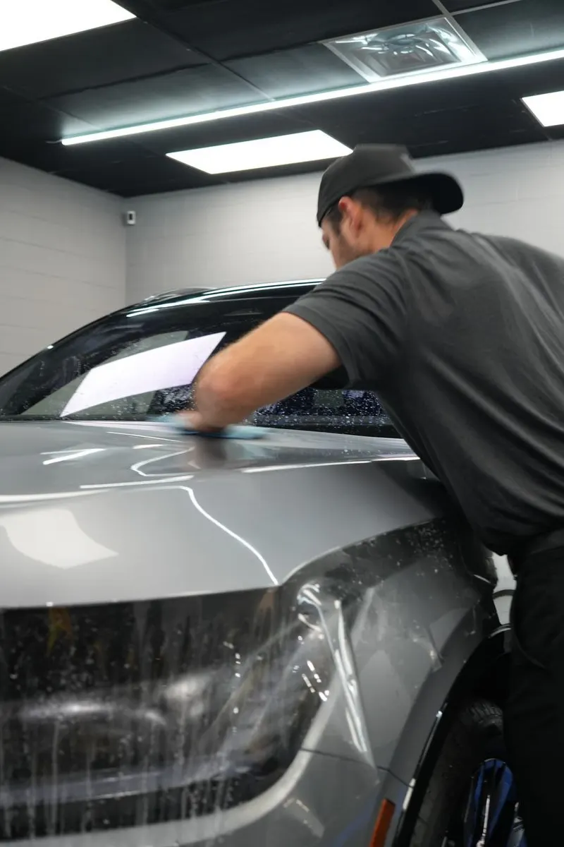 A technician wipes down a vehicle door panel with a cloth.
